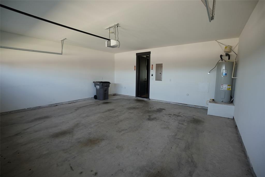 1764 Palladio Loop Princeton, TX 75407 - Photo 15 of 40 Spacious garage featuring a concrete floor, painted walls, overhead garage door opener, and a water heater