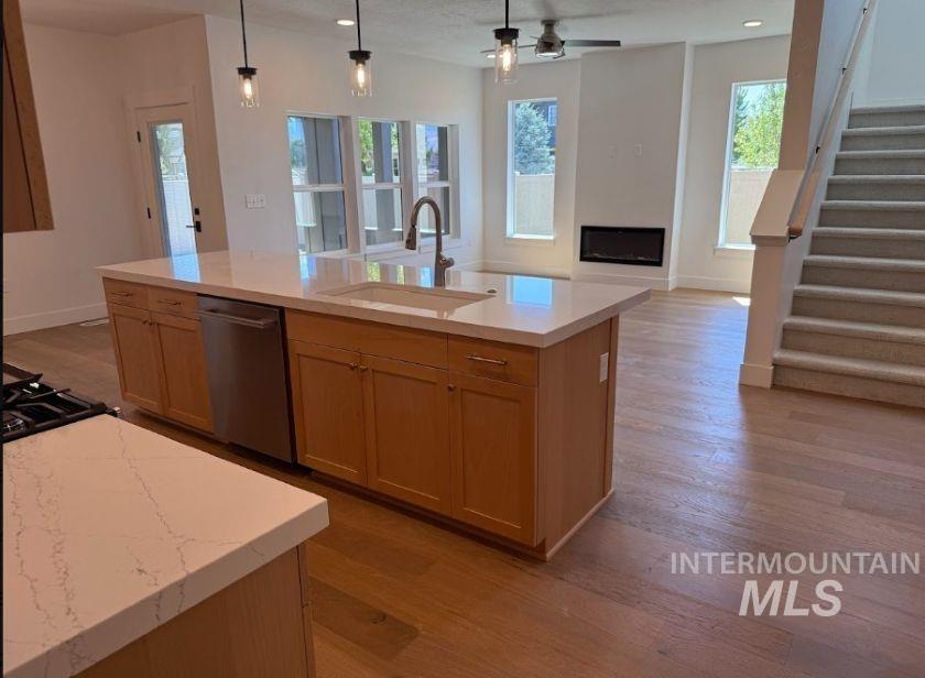 755 West Wrangler Street Meridian, ID 83646 - Photo 6 of 35 Kitchen island featuring a built-in stainless steel dishwasher, undermount sink with a gooseneck faucet, and light wood-finish cabinetry topped with a light-toned countertop