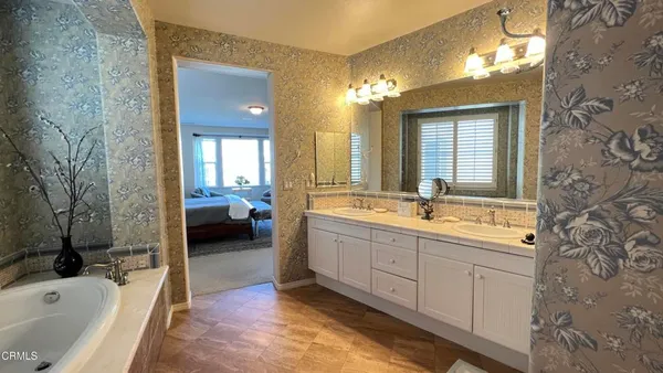 a spacious bathroom with a tub sink and mirror