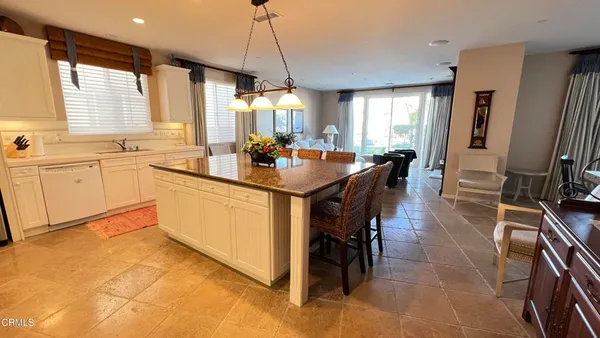 a kitchen with stainless steel appliances granite countertop a sink a stove a dining table and chairs