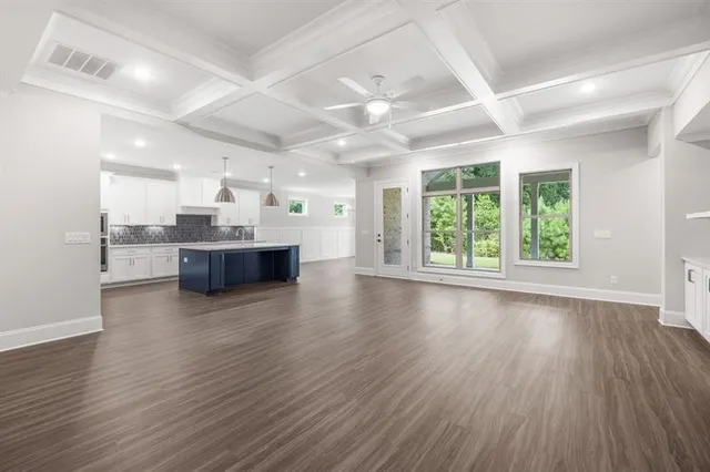 a large white kitchen with kitchen island a sink dishwasher a refrigerator and white cabinets with wooden floor