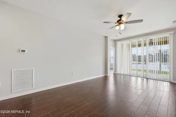 an empty room with wooden floor and a ceiling fan