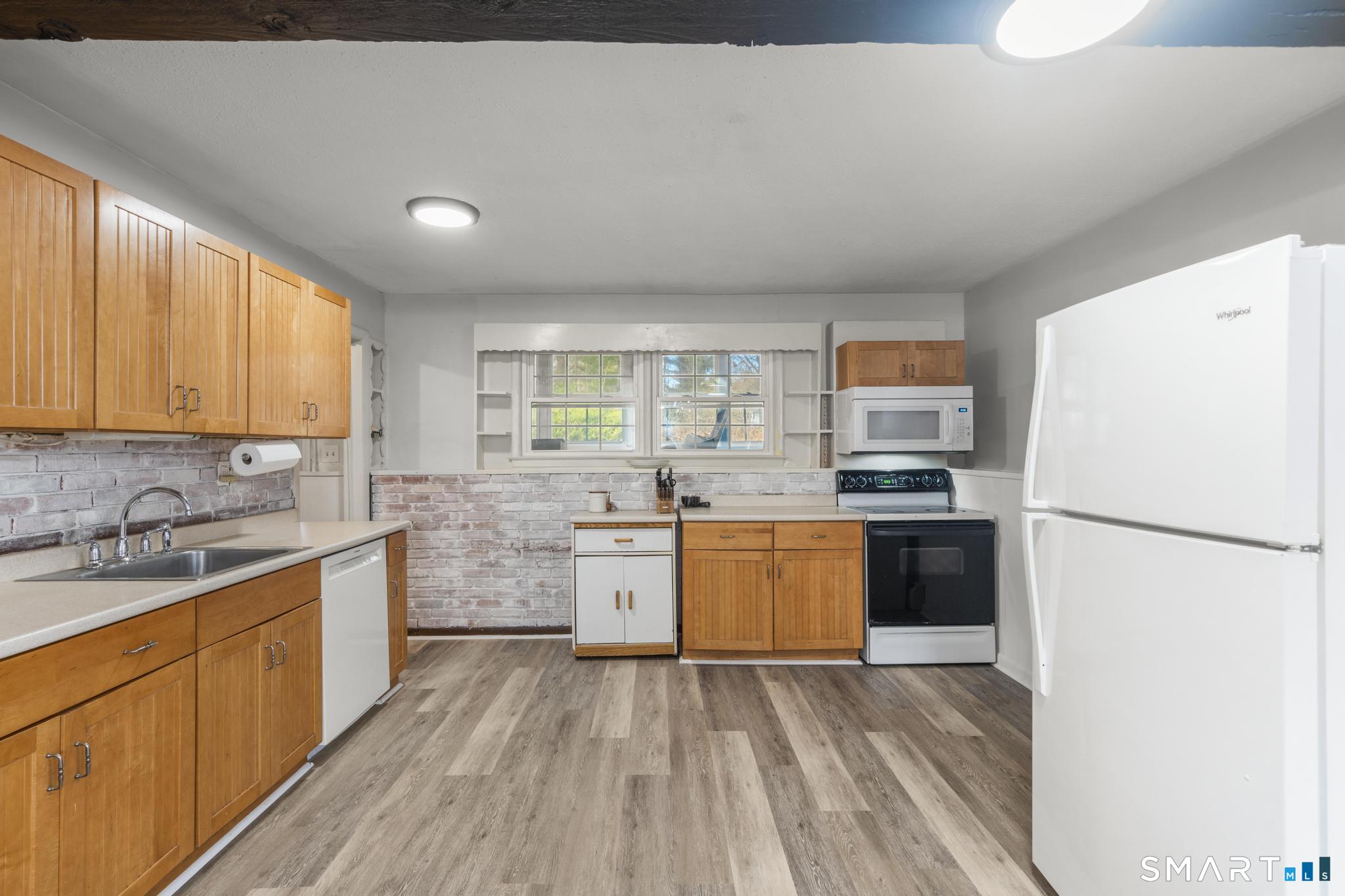 89 Green Meadow Road Milford, CT 06461 - Photo 8 of 31 a kitchen with stainless steel appliances granite countertop a refrigerator a sink dishwasher a stove top oven and a dining table with wooden floor