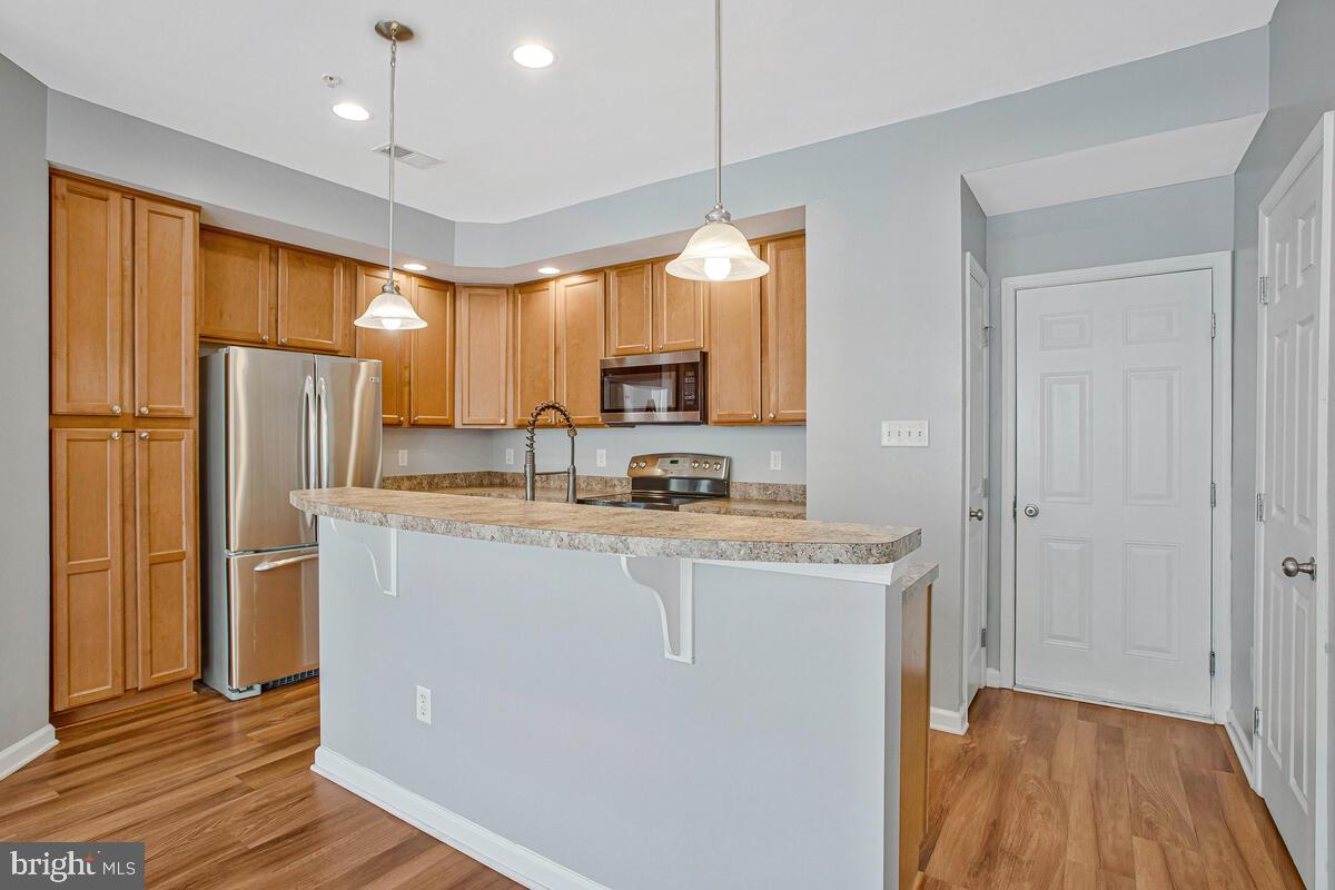 8049 Forest Ridge Drive, Unit 3 Chesapeake Beach, MD 20732 - Photo 11 of 40 a kitchen with stainless steel appliances granite countertop a refrigerator a sink dishwasher and a stove with wooden floor