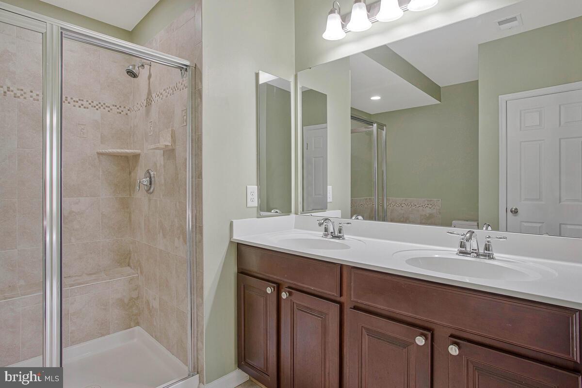 8049 Forest Ridge Drive, Unit 3 Chesapeake Beach, MD 20732 - Photo 23 of 40 a bathroom with a double vanity sink mirror and shower