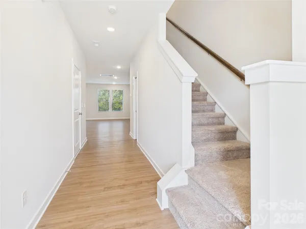 a kitchen with stainless steel appliances granite countertop a refrigerator a stove a sink dishwasher and white cabinets with wooden floor