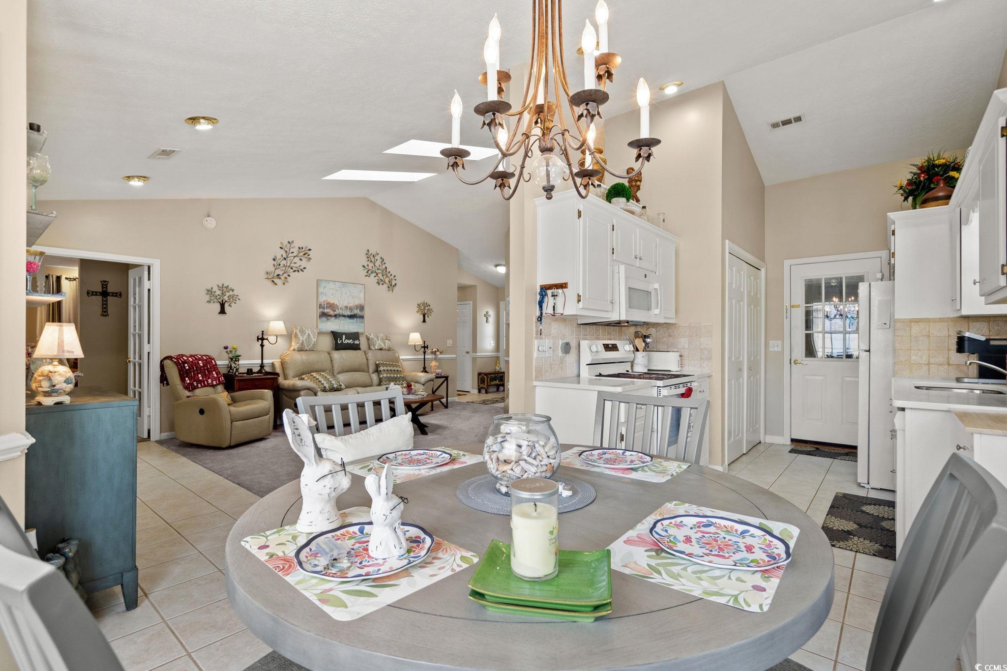 9533 Sullivan Drive Murrells Inlet, SC 29576 - Photo 12 of 40 Dining area with a chandelier, light tile patterned flooring, a skylight, and high vaulted ceiling