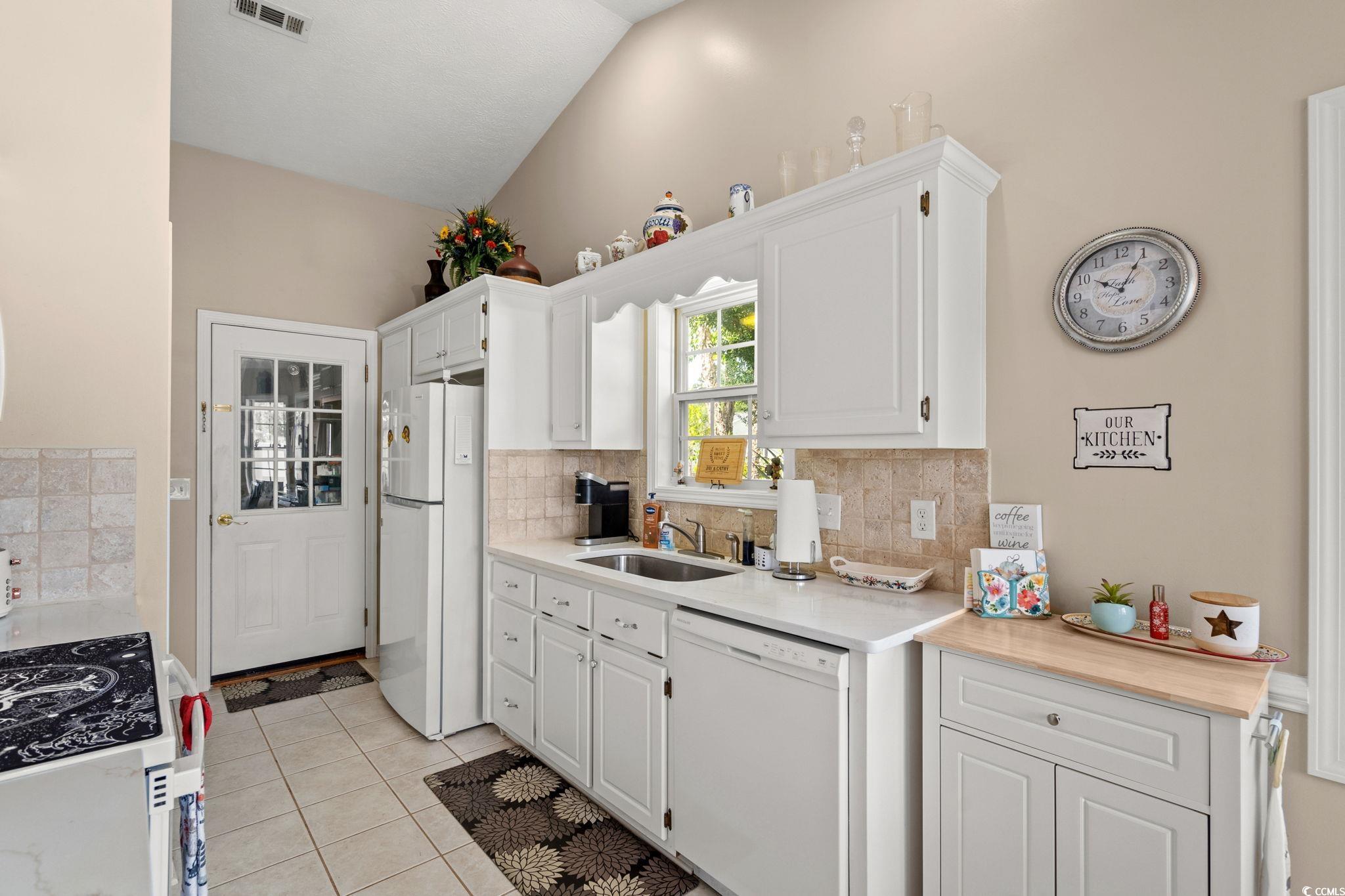 9533 Sullivan Drive Murrells Inlet, SC 29576 - Photo 13 of 40 Kitchen featuring white cabinets, white appliances, light tile patterned floors, and backsplash