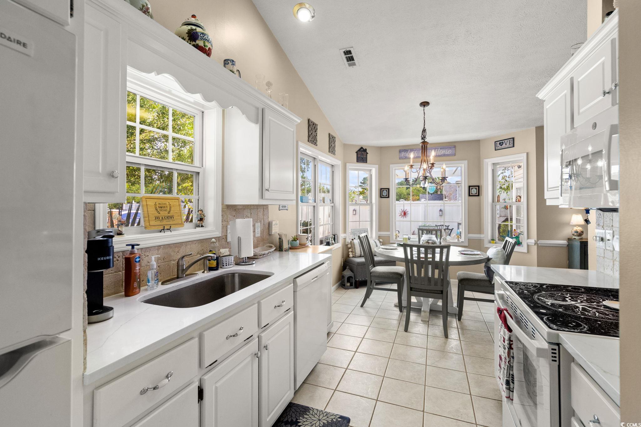9533 Sullivan Drive Murrells Inlet, SC 29576 - Photo 16 of 40 Kitchen featuring white appliances, white cabinetry, backsplash, light tile patterned floors, and lofted ceiling