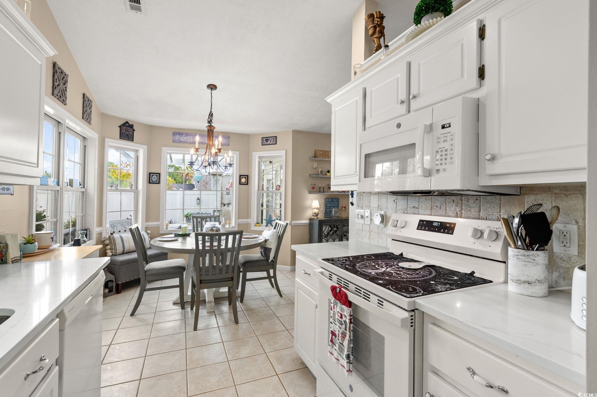 9533 Sullivan Drive Murrells Inlet, SC 29576 - Photo 17 of 40 Kitchen featuring white appliances, white cabinetry, light tile patterned floors, decorative light fixtures, and a chandelier