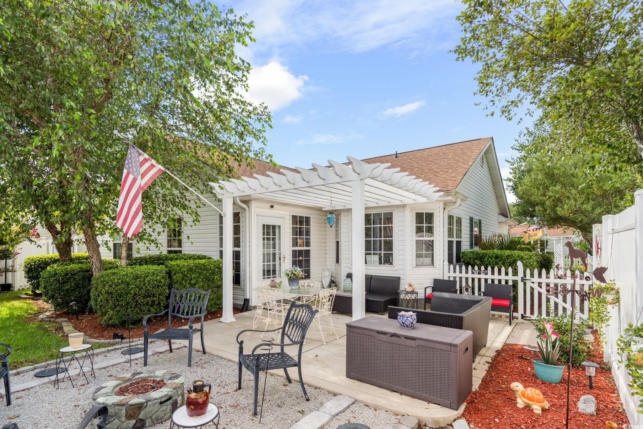 9533 Sullivan Drive Murrells Inlet, SC 29576 - Photo 27 of 40 Back of property with a patio area, an outdoor living space with a fire pit, a pergola, and roof with shingles