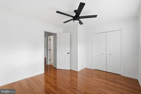 a view of a room with wooden floor and a ceiling fan