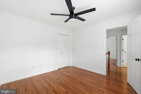 a view of a room with wooden floor and a ceiling fan