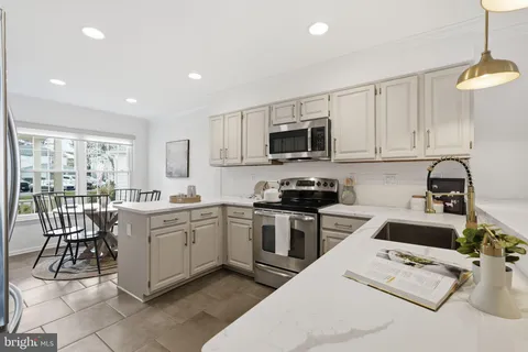 a kitchen with a sink a counter top space appliances and cabinets