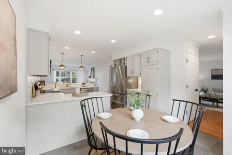 a kitchen with stainless steel appliances granite countertop a dining table chairs and a refrigerator