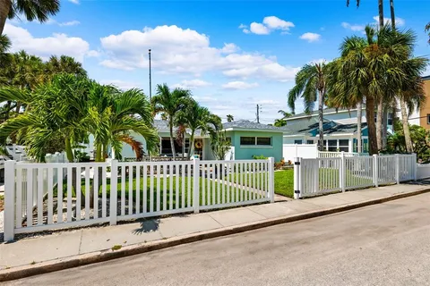 a view of a house with a small yard and palm trees
