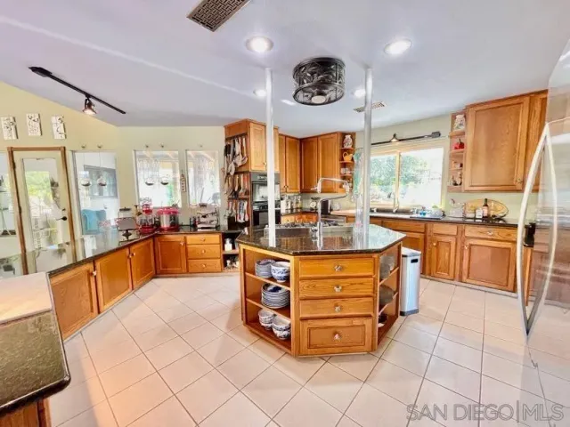 a large kitchen with stainless steel appliances kitchen island granite countertop a large counter top and a view of living room