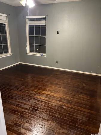 a view of an empty room with wooden floor and windows