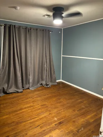 a view of room with hardwood floor and a ceiling fan