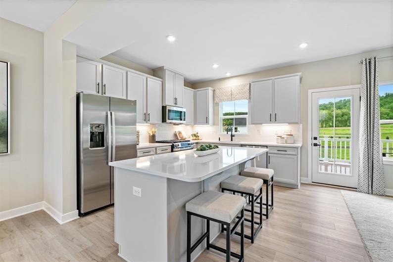 8013 Chief Way Mars, PA 16046 - Photo 4 of 18 a kitchen with stainless steel appliances granite countertop a refrigerator a stove a sink a dining table and chairs with wooden floor