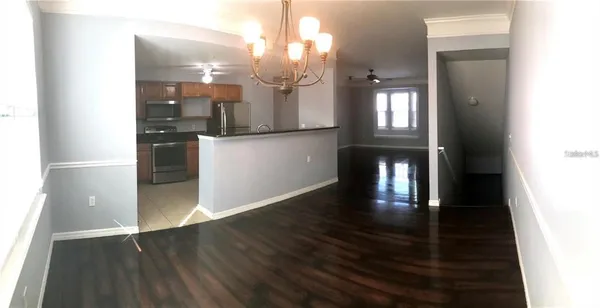 a view of a hallway with wooden floor and a kitchen