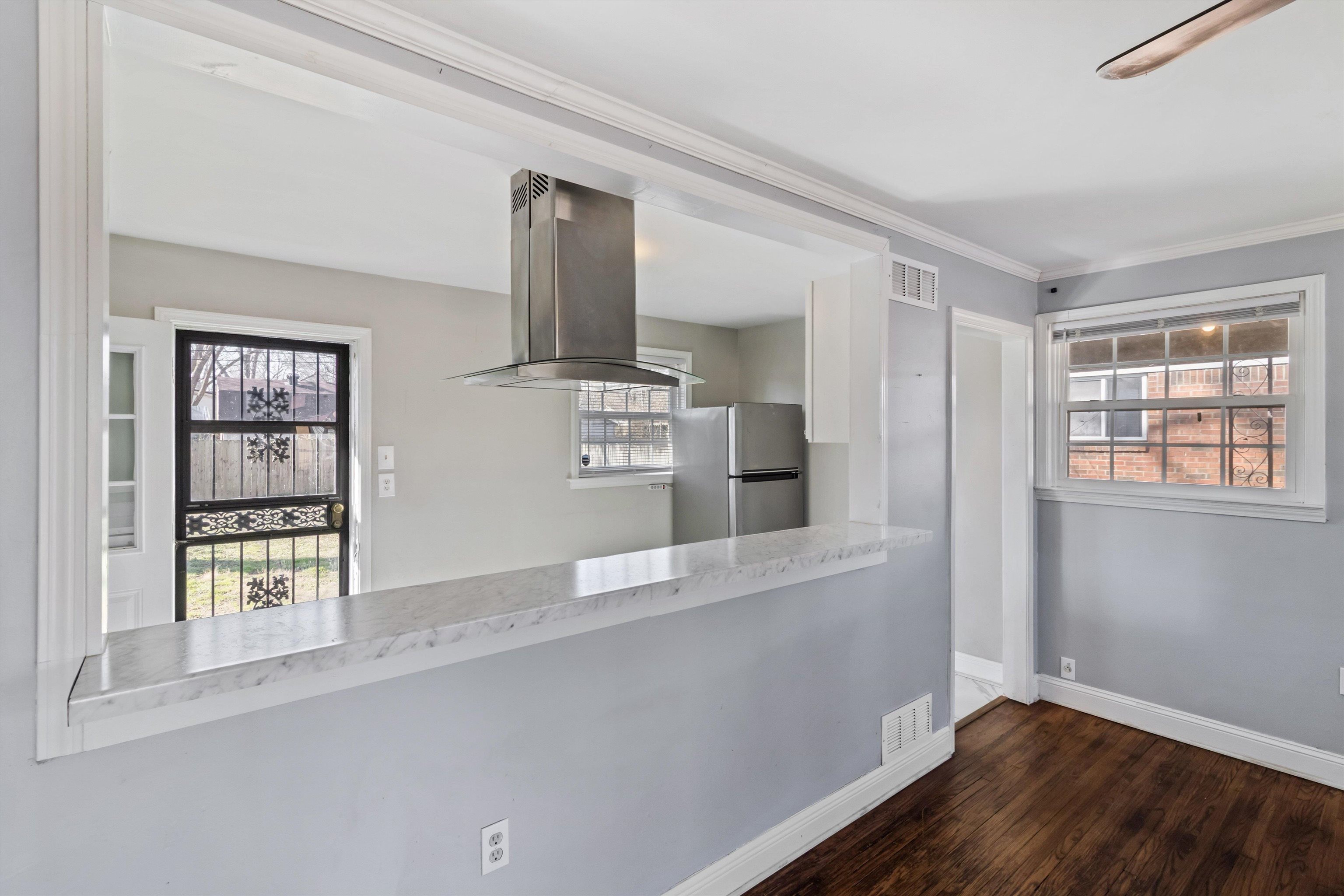 517 Malboro Road Memphis, TN 38120 - Photo 8 of 25 Kitchen with island range hood, freestanding refrigerator, dark wood-style flooring, light countertops, and plenty of natural light