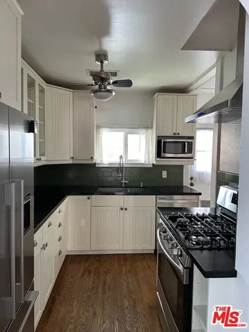 a kitchen with stainless steel appliances a sink a stove a refrigerator and cabinets