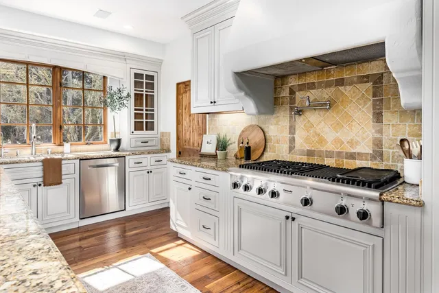 a kitchen with granite countertop a sink and white cabinets