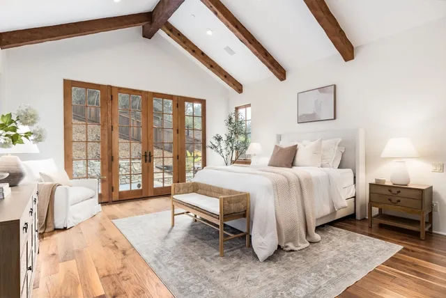 a spacious bedroom with a large bed and a flat tv screen on dresser