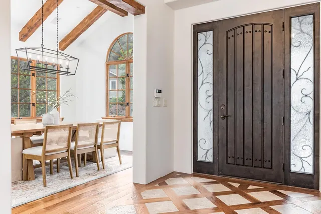 a dining room with wooden floor a chandelier a wooden table and chairs