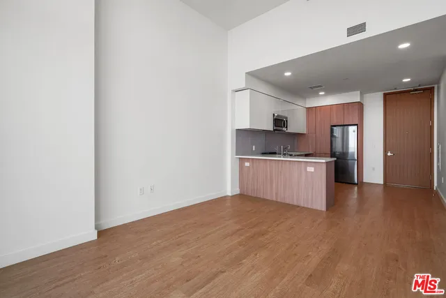 a large kitchen with stainless steel appliances granite countertop a large counter top and a wooden floor