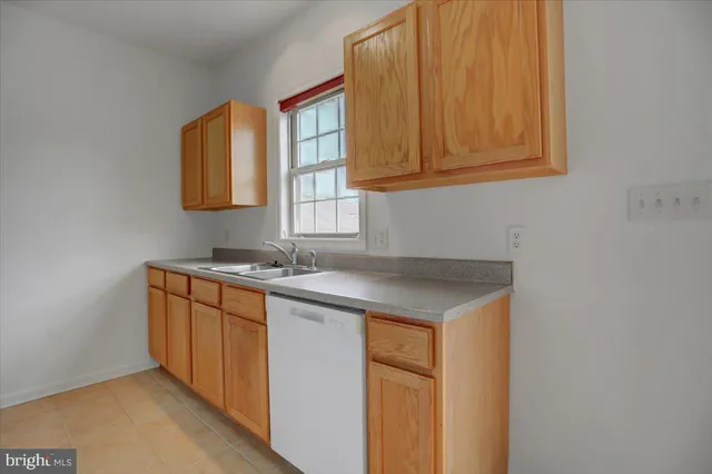 a utility room with stainless steel appliances granite countertop a sink and a window
