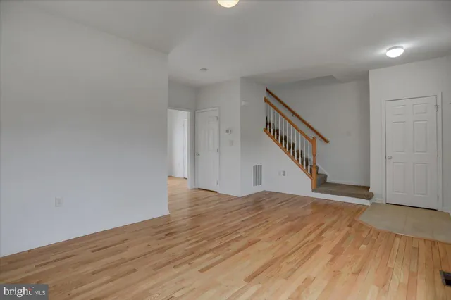 a view of an empty room with wooden floor and stairs