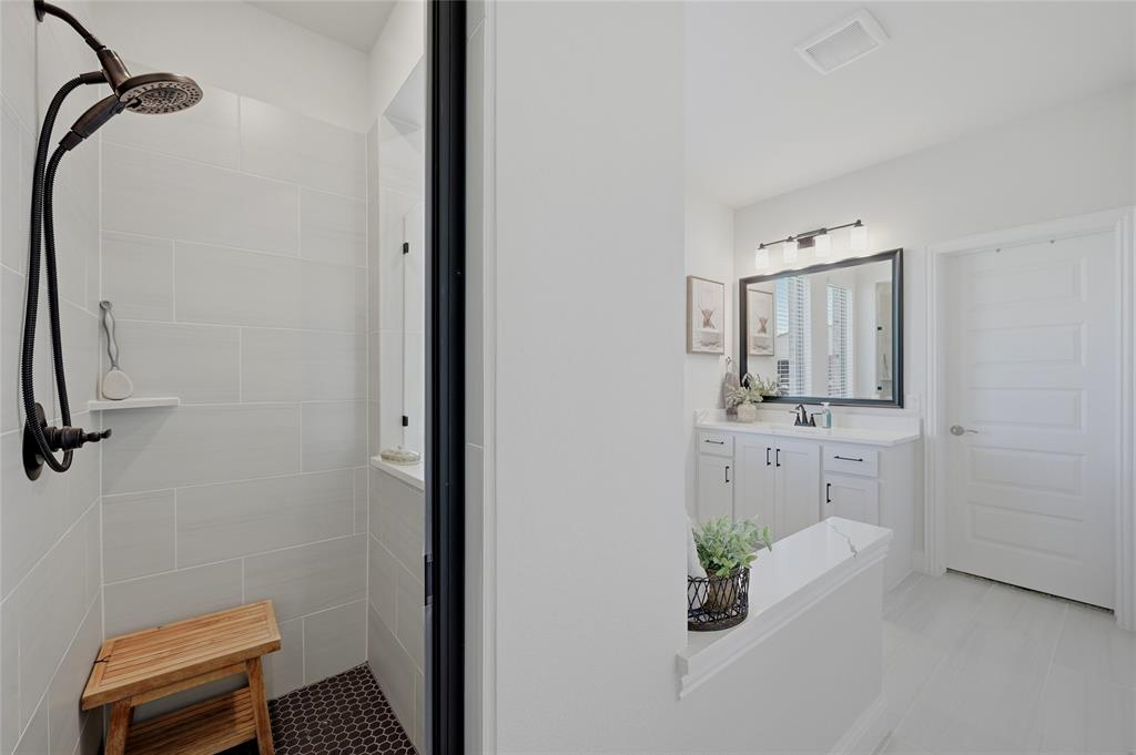 864 Shadow Valley Road Whitesboro, TX 76273 - Photo 26 of 40 Bathroom featuring a walk-in shower with vertical tile surround and dark penny tile flooring, a dark bronze shower fixture, and a built-in shower shelf