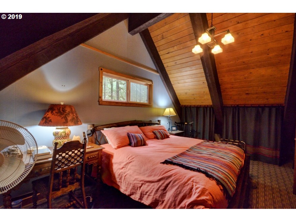 75191 East E Road Rhododendron, OR 97049 - Photo 23 of 32 a bedroom with a bed and a chandelier