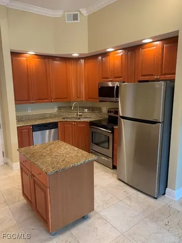a kitchen with kitchen island a counter top space cabinets stainless steel appliances and a window