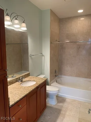 a bathroom with a granite countertop sink a toilet a mirror and bathtub
