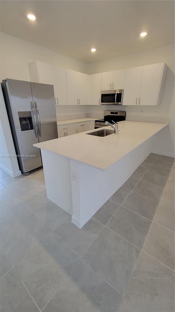 26430 Southwest 148th Court, Unit 26430 Homestead, FL 33032 - Photo 8 of 21 a kitchen with kitchen island white cabinets and refrigerator