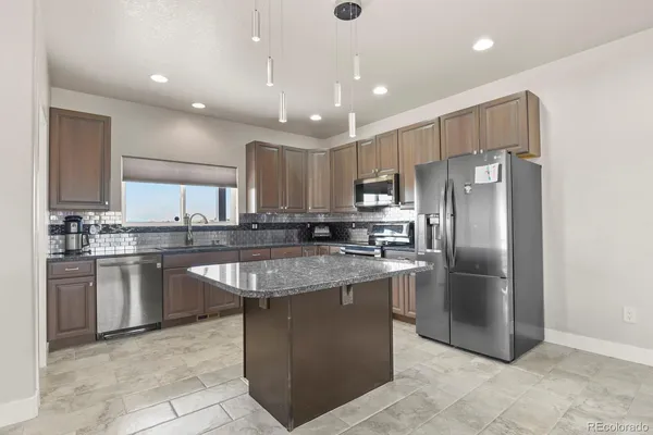 a kitchen with stainless steel appliances granite countertop a refrigerator a sink a stove a microwave and island