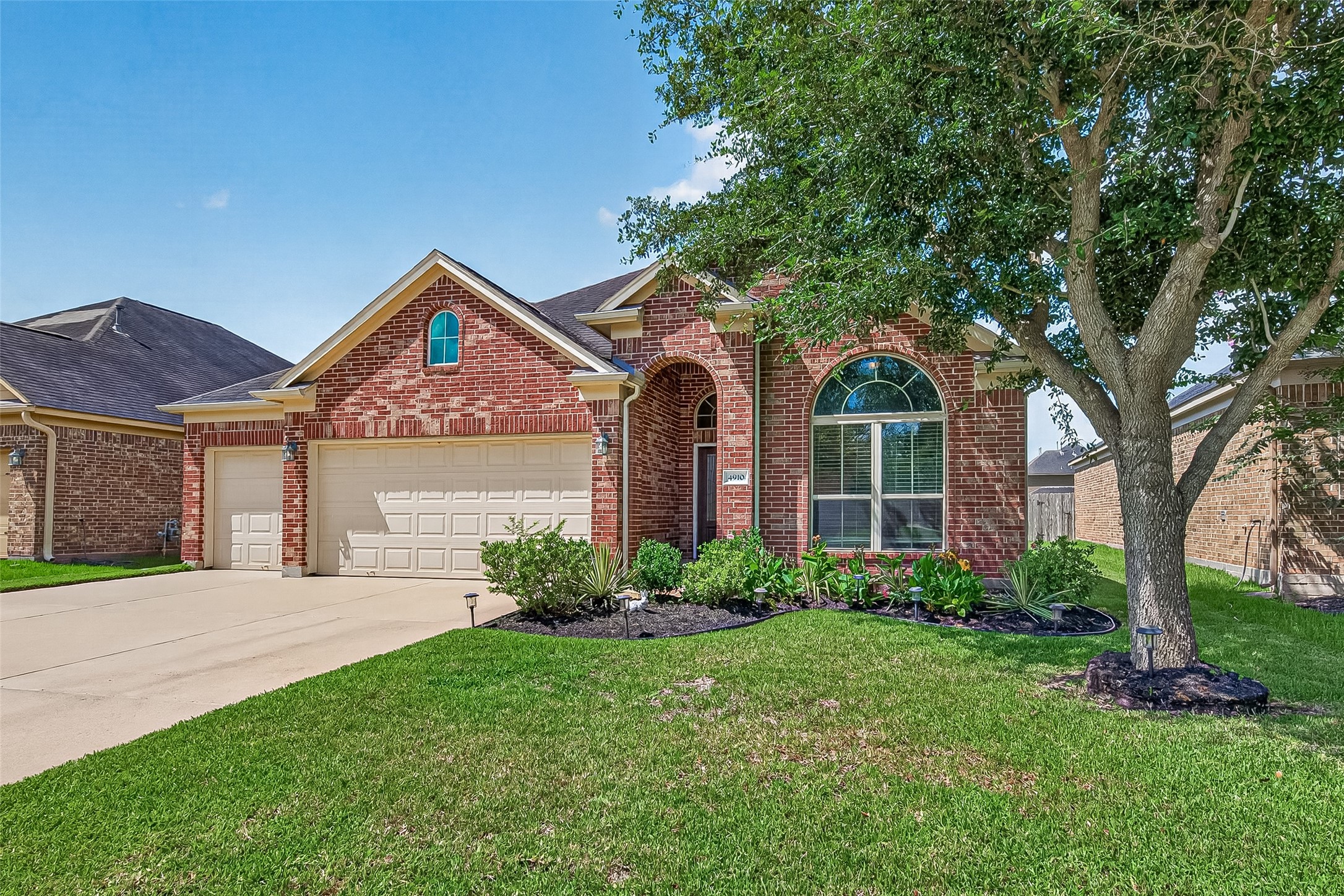 4910 Culver Lane Rosenberg, TX 77471 - Photo 48 of 50 Well-maintained lawn, with lush, thick grass, and mature tree. The large arched window and tidy landscaping add to its inviting exterior.