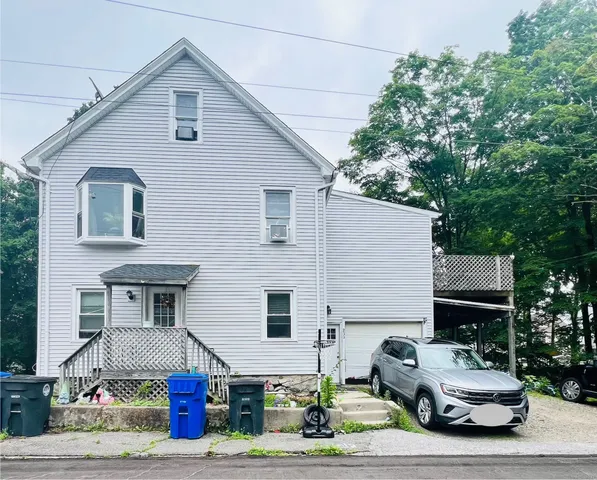a front view of a house with garden and parking