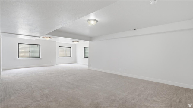 2038 East Ranch Road Eagle Mountain, UT 84005 - Photo 35 of 66 Spacious room featuring light-colored carpeting, multiple windows with horizontal blinds, and flush-mount ceiling lighting fixtures