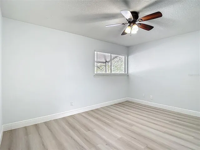 an empty room with a window and a fan