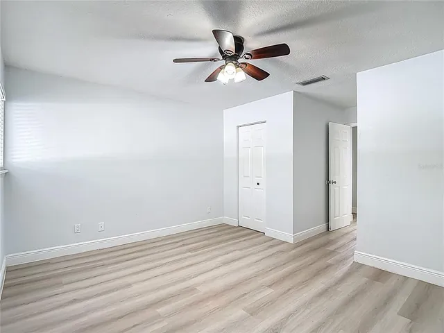 a view of a room with wooden floor and a ceiling fan