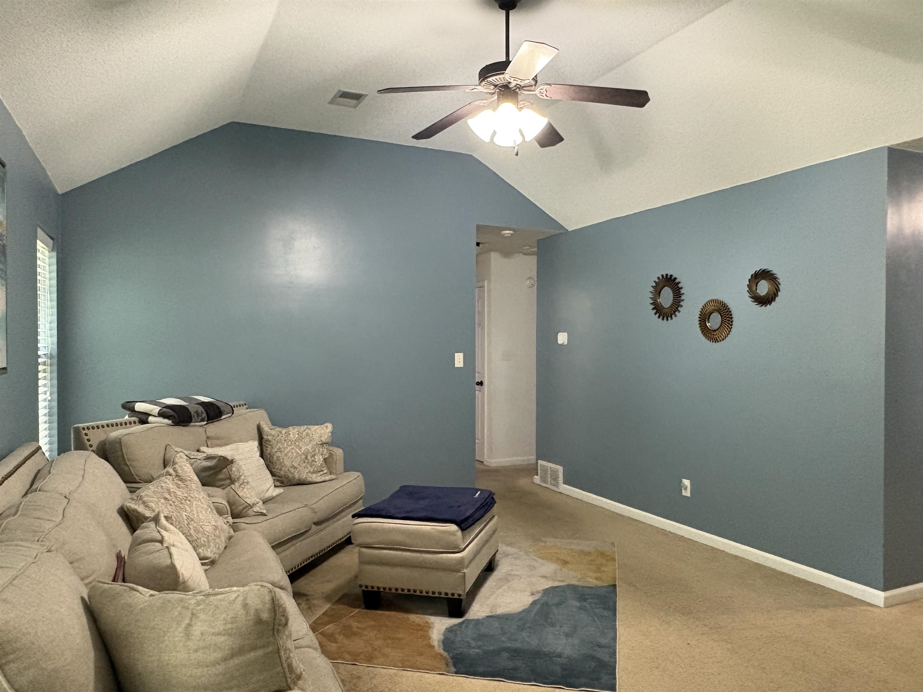 4356 Cedar Hills Road Memphis, TN 38135 - Photo 12 of 29 Spacious living area featuring a vaulted ceiling with a ceiling fan, light blue wall paint, and beige carpeting