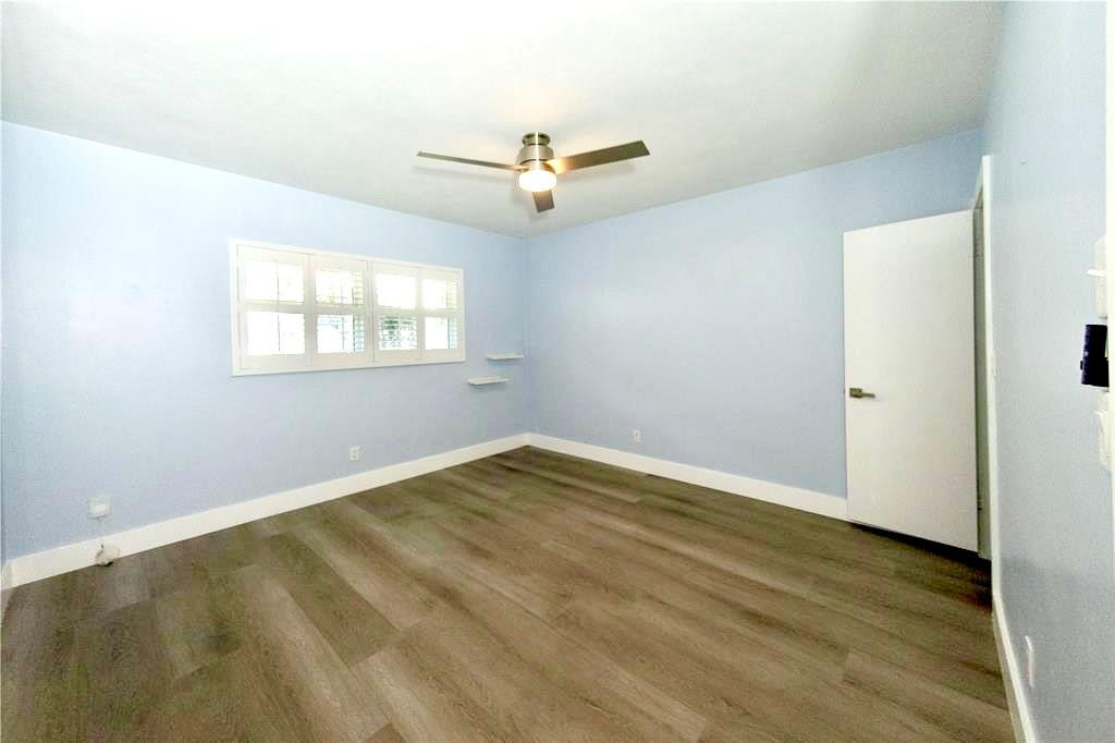 1991 Northeast 32nd Street, Unit 18 Lighthouse Point, FL 33064 - Photo 14 of 39 an empty room with wooden floor ceiling fan and windows