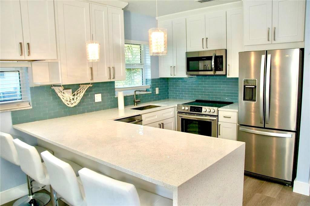 1991 Northeast 32nd Street, Unit 18 Lighthouse Point, FL 33064 - Photo 19 of 39 a kitchen with kitchen island a stove a sink and a refrigerator