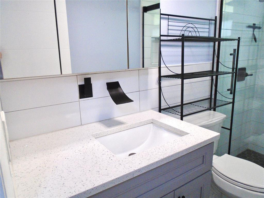 1991 Northeast 32nd Street, Unit 18 Lighthouse Point, FL 33064 - Photo 23 of 39 a bathroom with a granite countertop sink a toilet and shower