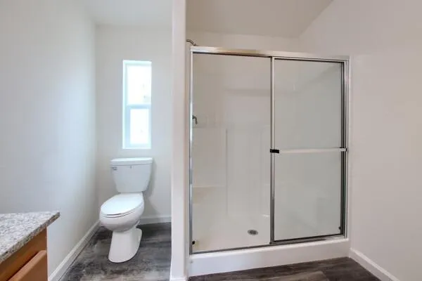 a bathroom with a toilet a window and shower
