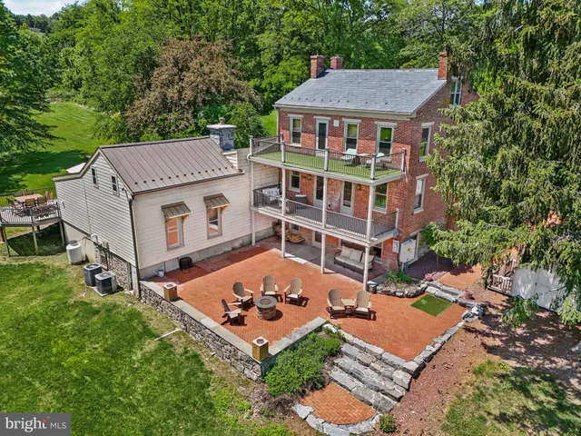 a view of a backyard with table and chairs potted plants and large tree